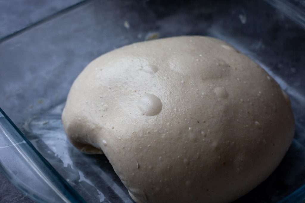 Coild folded dough in a glass dish.