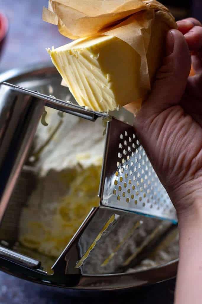 Grating frozen butter into the flour mixture.