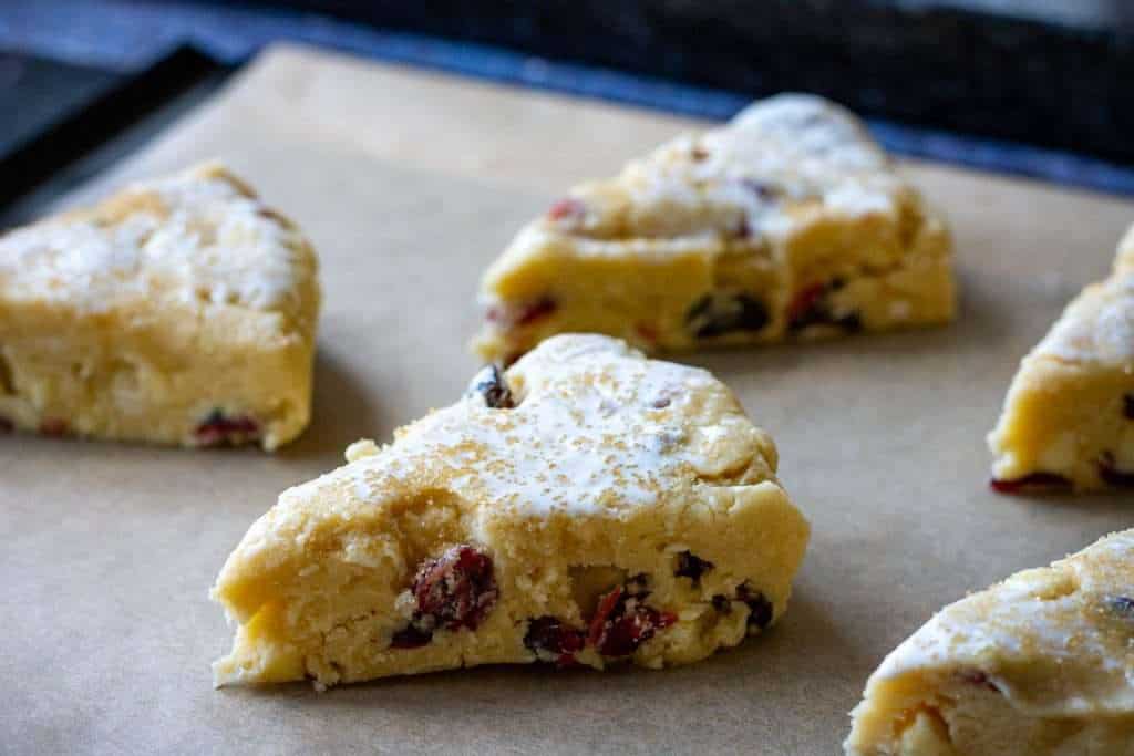 White chocolate cherry scones arranged on a baking sheet lined with parchment paper.