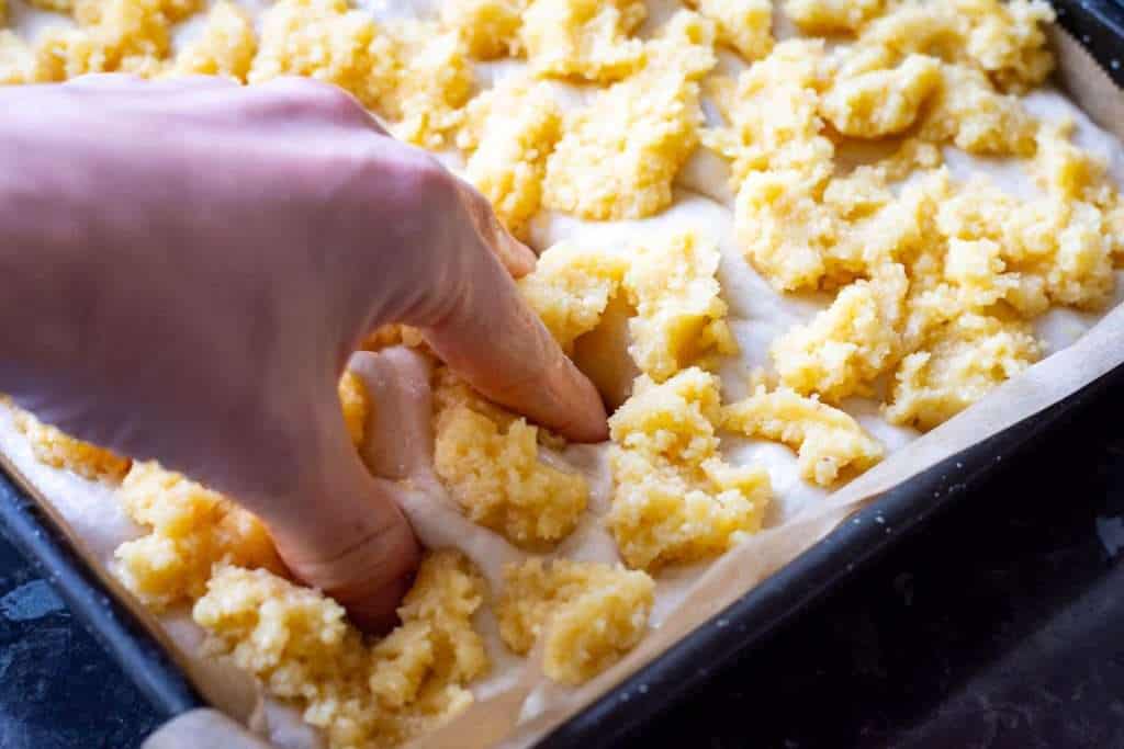 Dimpling sourdough focaccia with almond filling with oiled fingers.