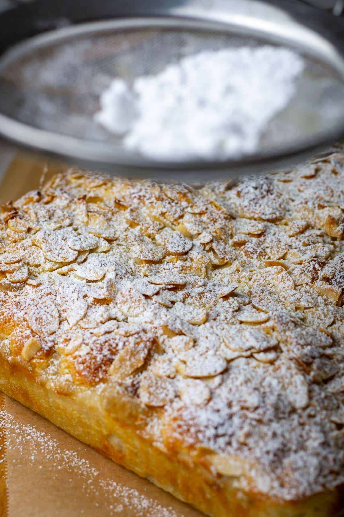 Dusting almond sourdough focaccia with powdered sugar.