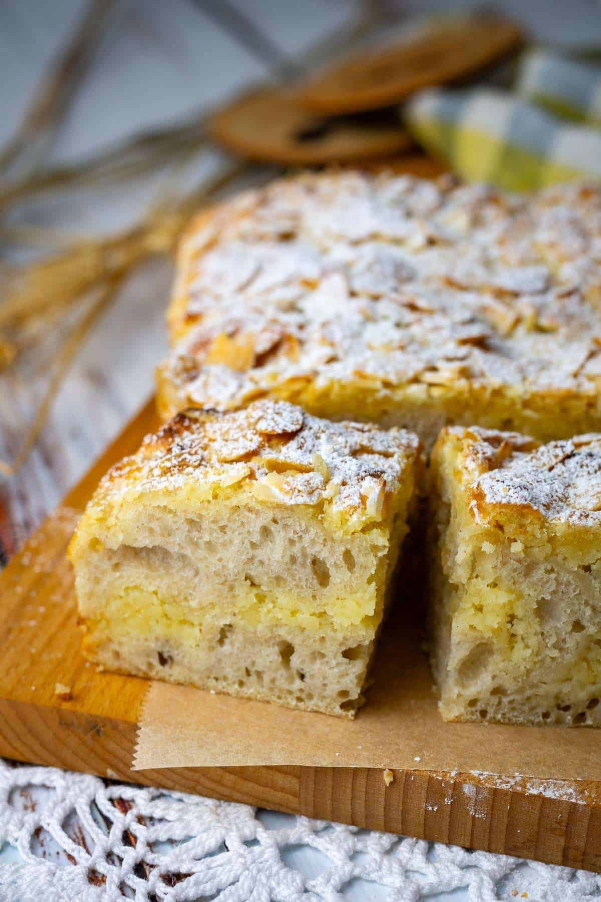 Almond Croissant Sourdough Focaccia cut into squares on a wooden chopping board.