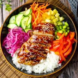 Teriyaki chicken poke bowl on a straw mat.