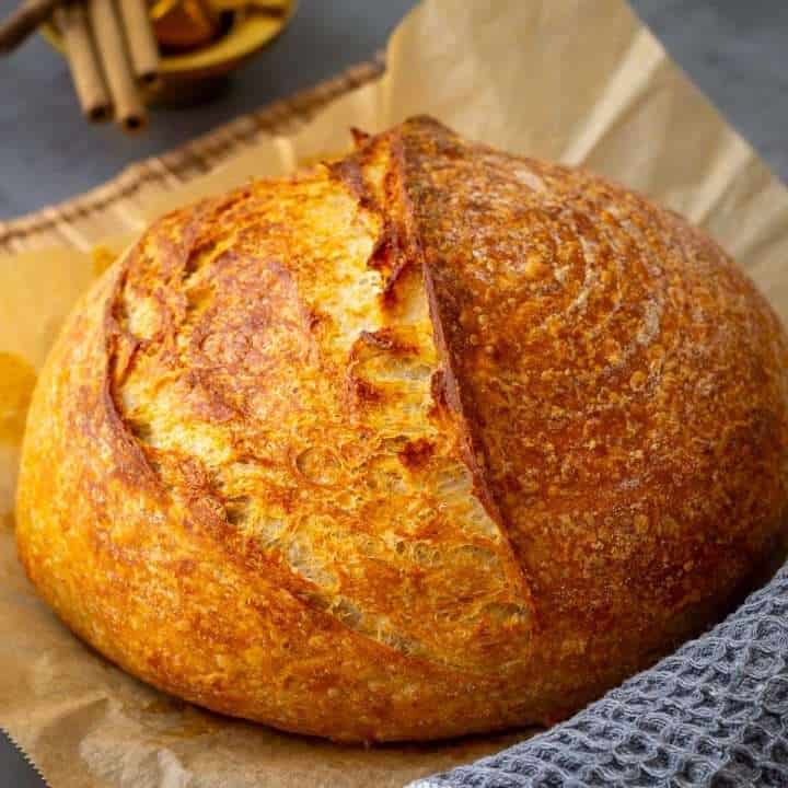 Golden crusted Parmesan Sourdough Bread on a piece of parchment paper.
