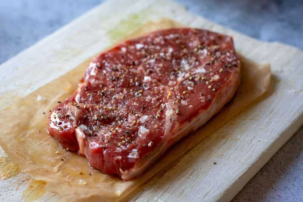 uncooked Sirloin steak on a chopping board.