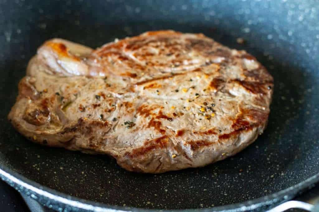 Cooking the steak in a frying pan.