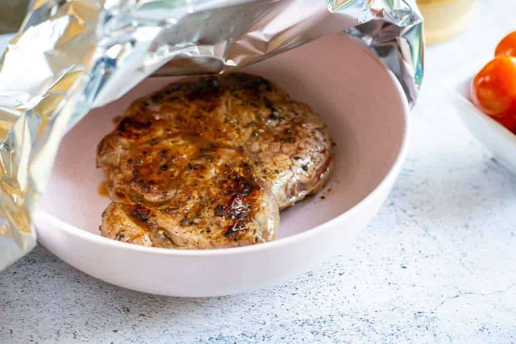 Cooked Steak resting in a bowl covered with foil.