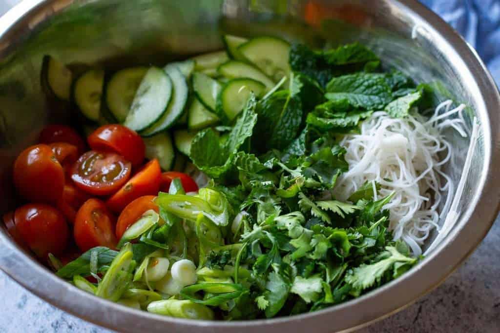 Salad vegetables and noodles in a large mixing bowl.