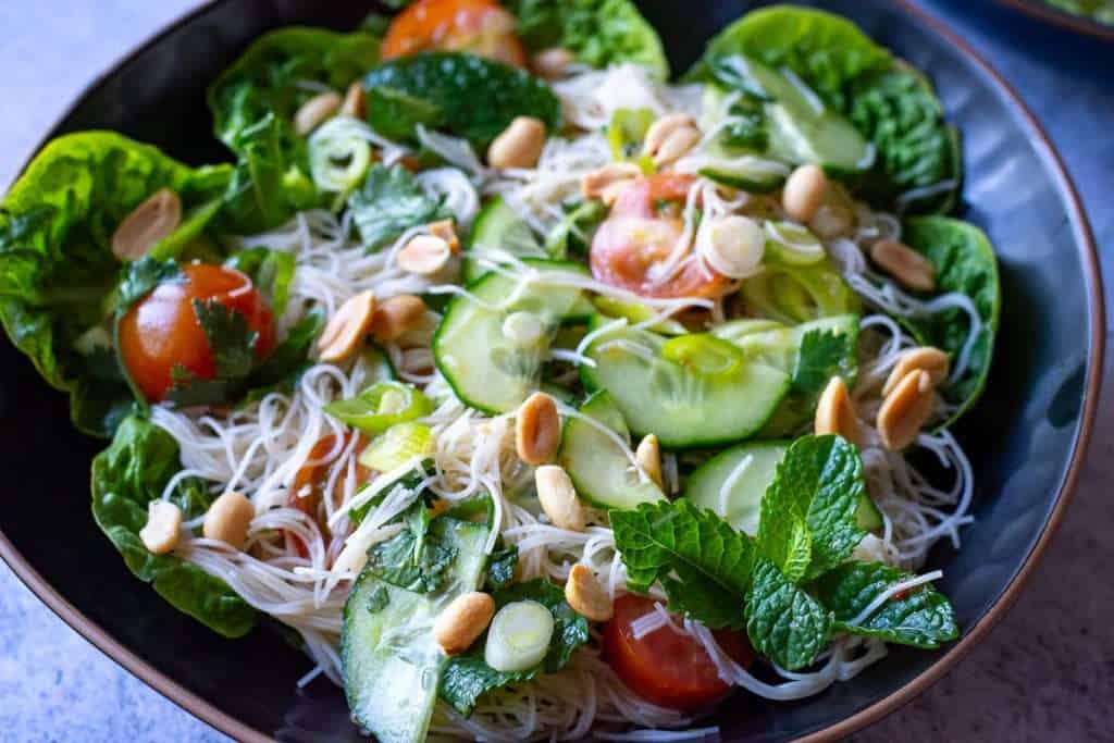 Tossed thai noodle salad in a black bowl.
