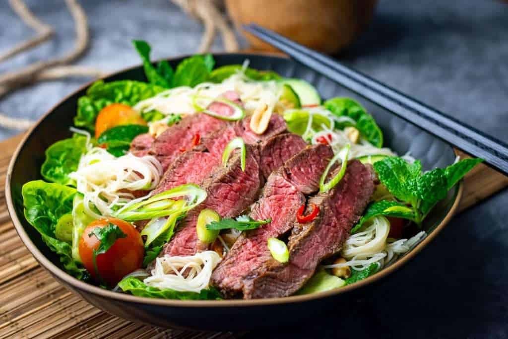 Thai beef noodle salad topped with sliced steak.