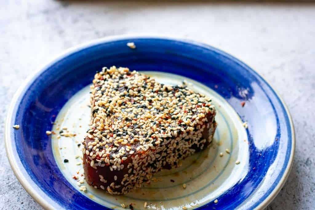 Sesame crusted Ahi tuna steak on a small blue plate.