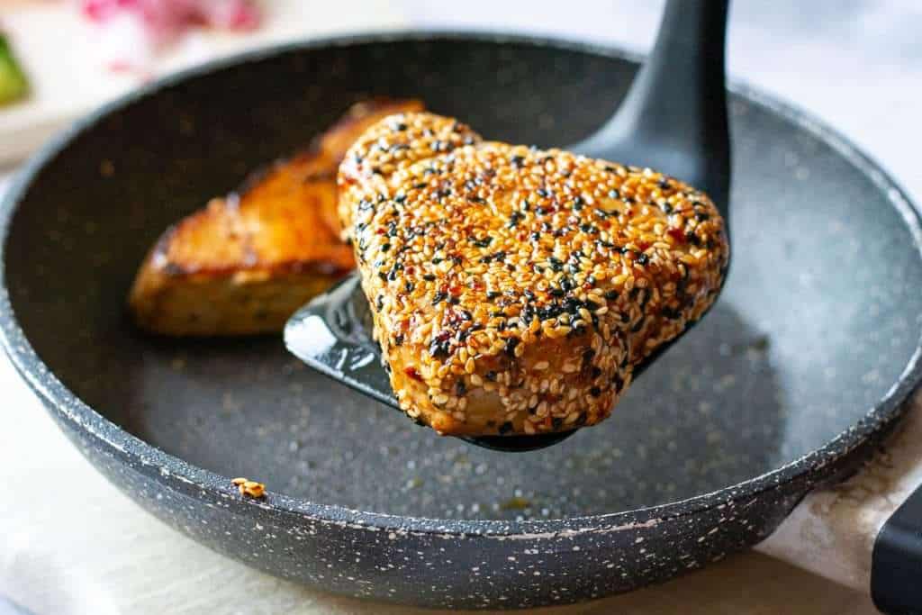 Seared tuna stek lifted out of the pan.