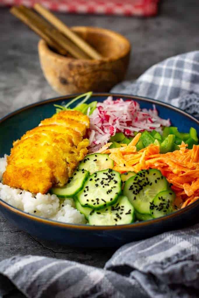 Rice and vegetables topped with sliced panko chicken breast.
