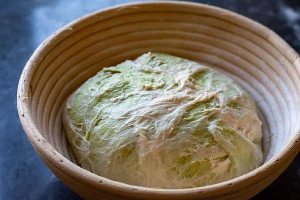 Shaped Matcha Sourdough in a banneton basket.