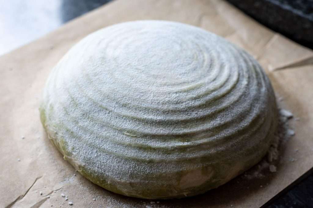 Matcha swirl sourdough inverted onto a parchemtn paper sheet.