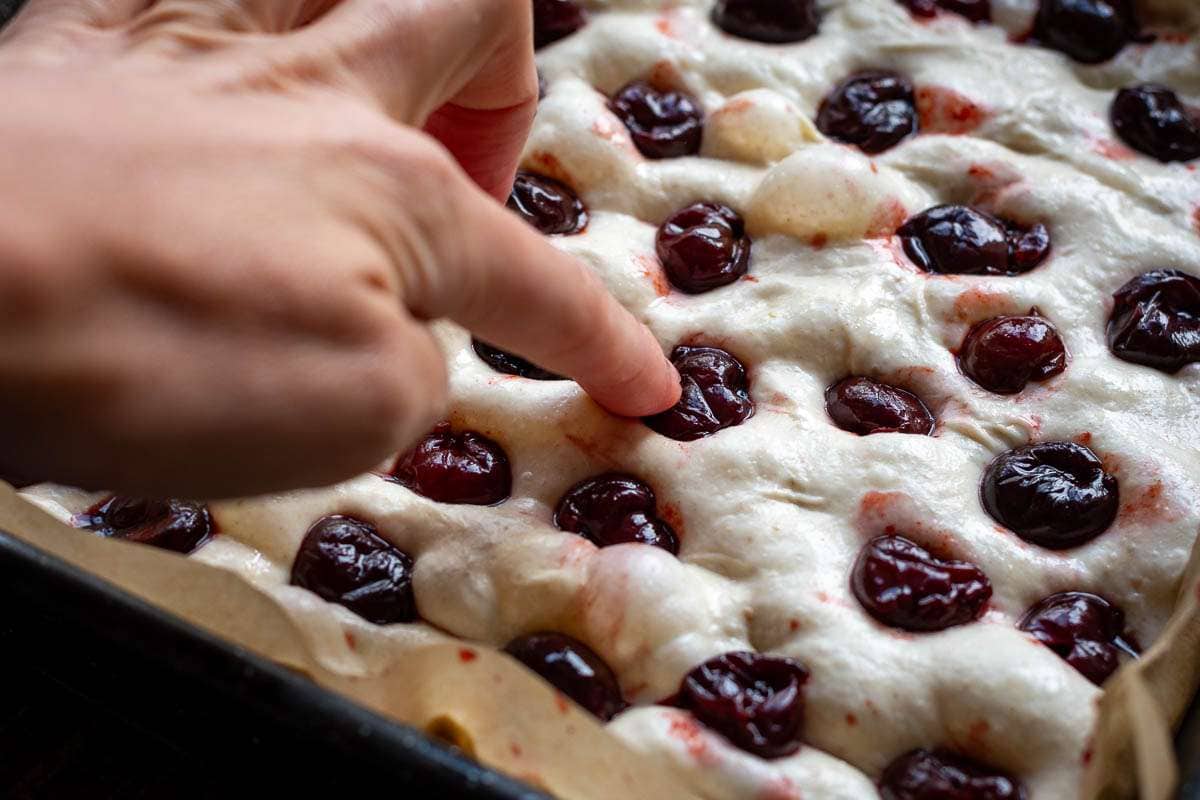 Pressing cherries into sourdough focaccia.