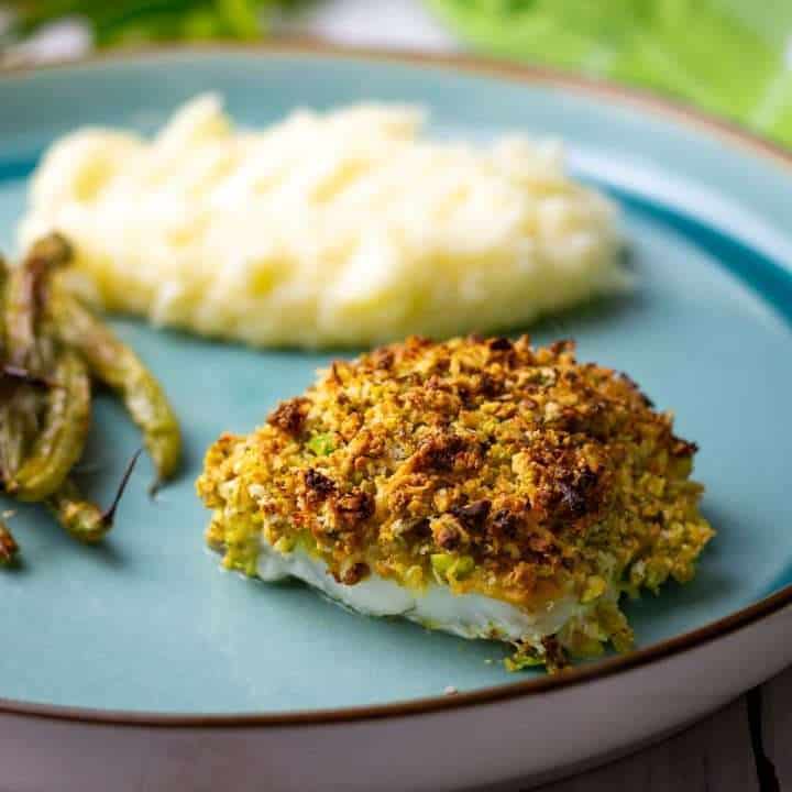 Pistachio Crusted Cod served with mashed potatoes on a teal-coloured plate.