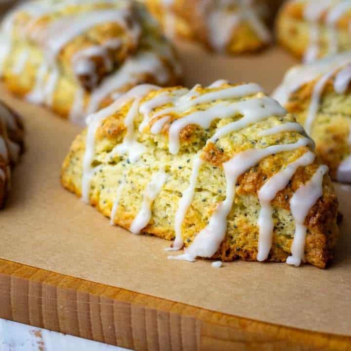Sourdough Lemon Poppy Seed Scones With lemon glaze on a wooden board.