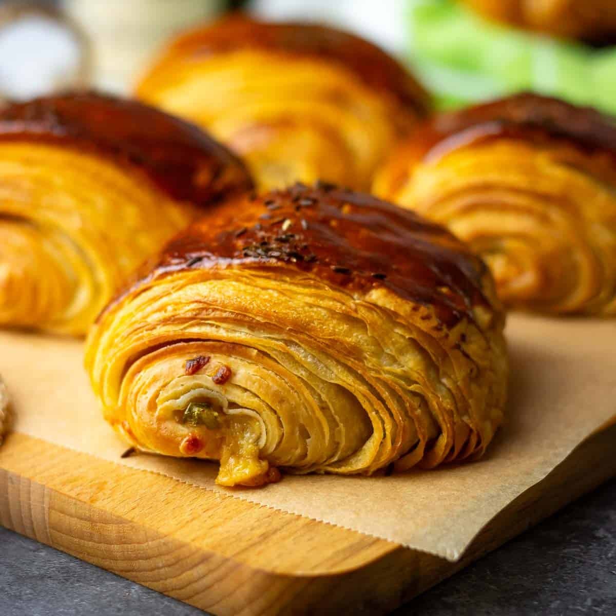 Smoked cheddar and jalapeno sourdough croissants on a wooden board.