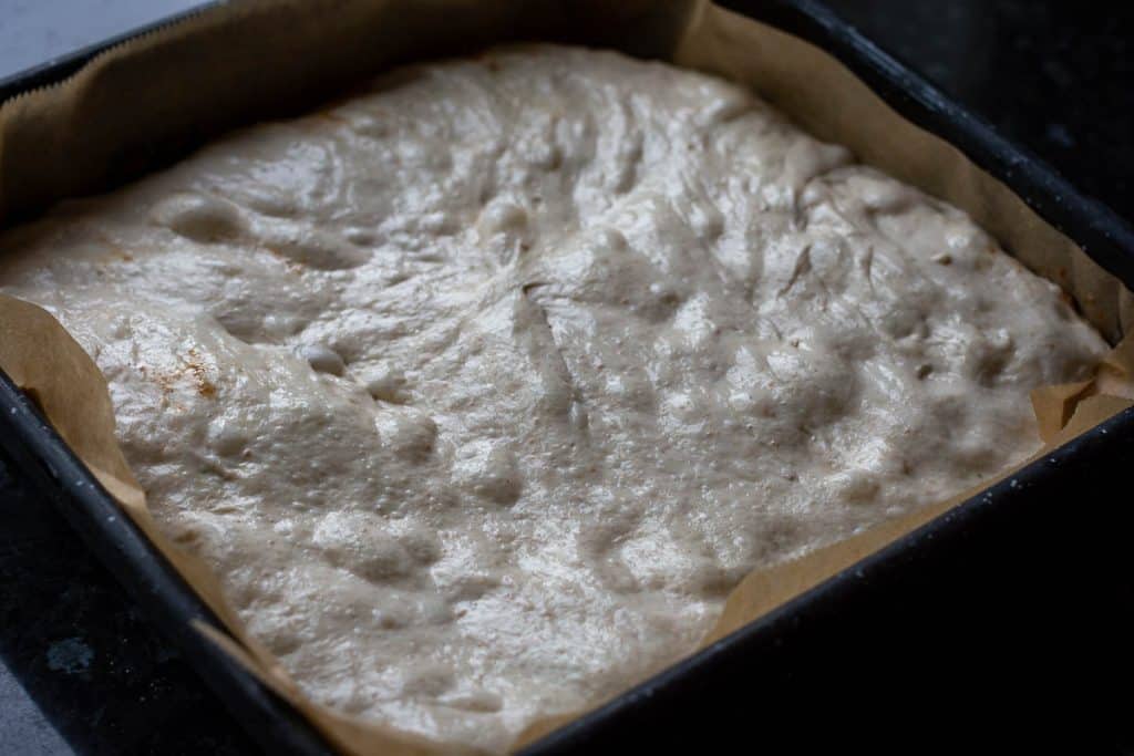 Cinnamon sourdough focaccia dough in a square baking tray.