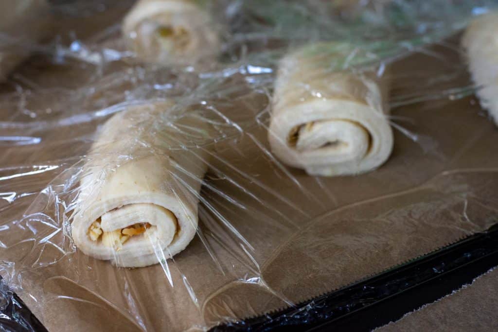 Sourdough croissants lightly covered with oiled plastic wrap.