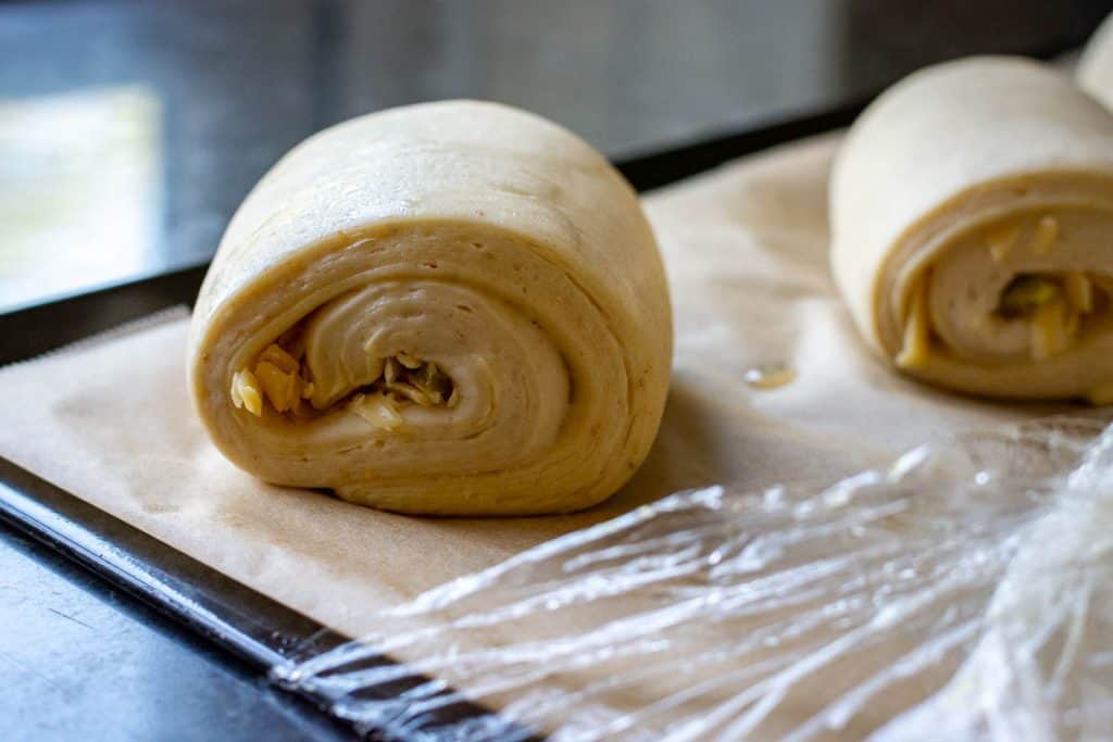 Jalapeno and smoked cheddar sourdough croissants after second proof on a baking sheet lined with parchment paper.