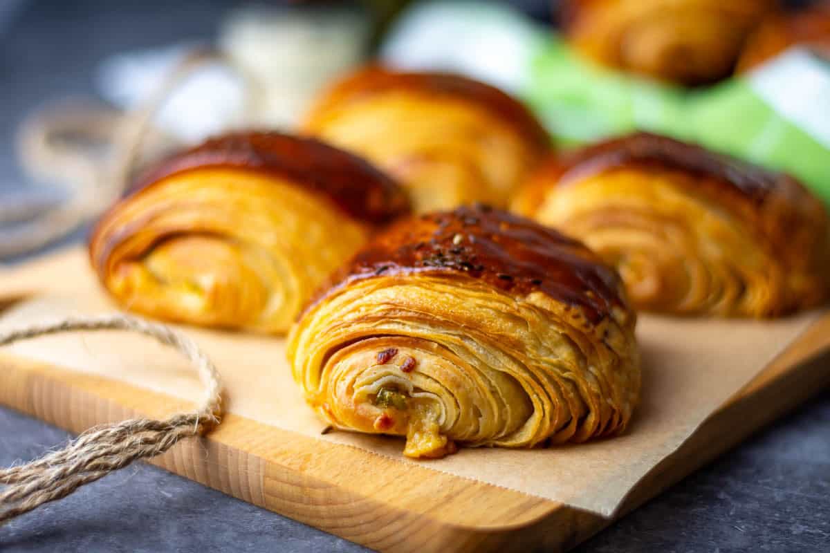 Smoked cheddar and jalapeno sourdough croissants on a wooden board.