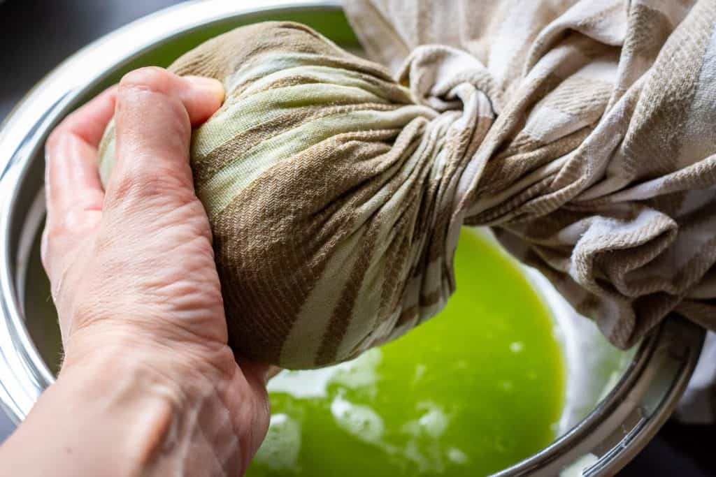 Squeezing the moisture out of the grated courgettes.