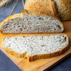 Sliced Lemon and Poppy Seed Sourdough Bread on a wooden board.