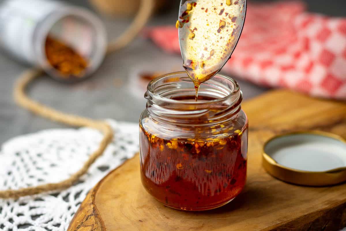 Homemade hot honey with smoked paprika being spooned into a small jar.