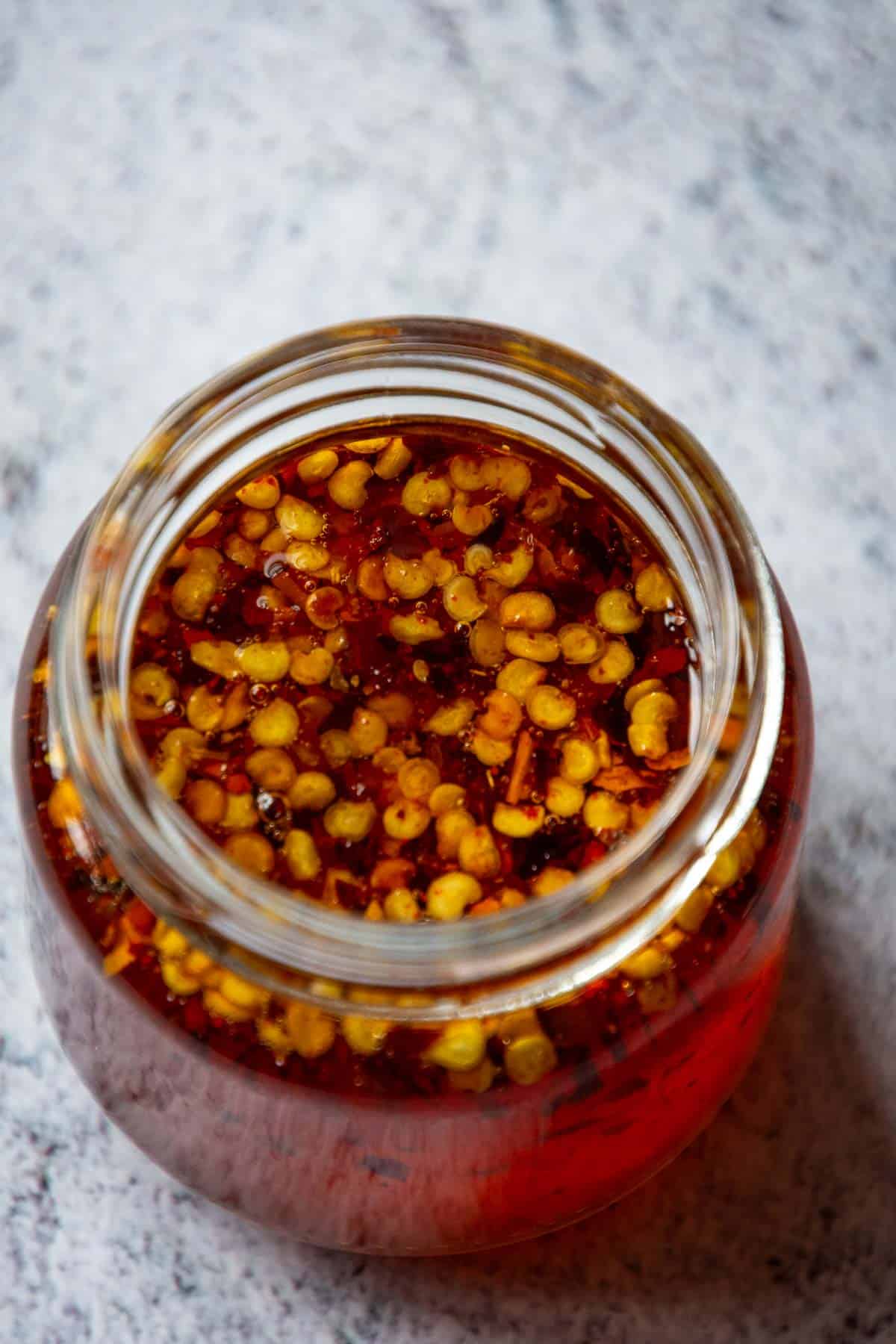 Chilli flakes on top of the hot honey in a glass jar.