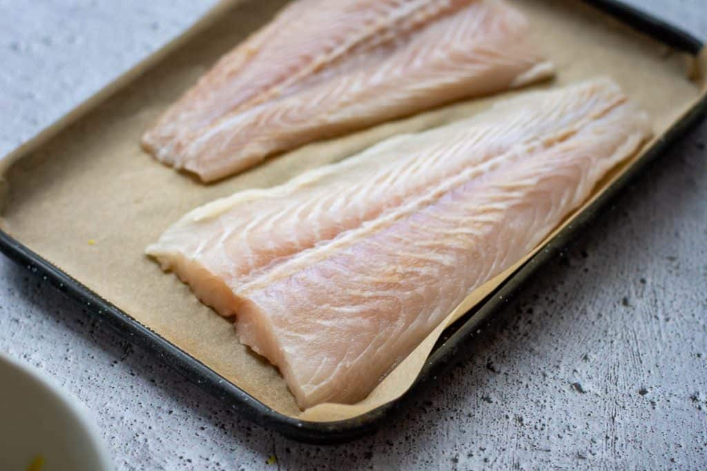 Basa filets on a parchment paper lined baking tray.