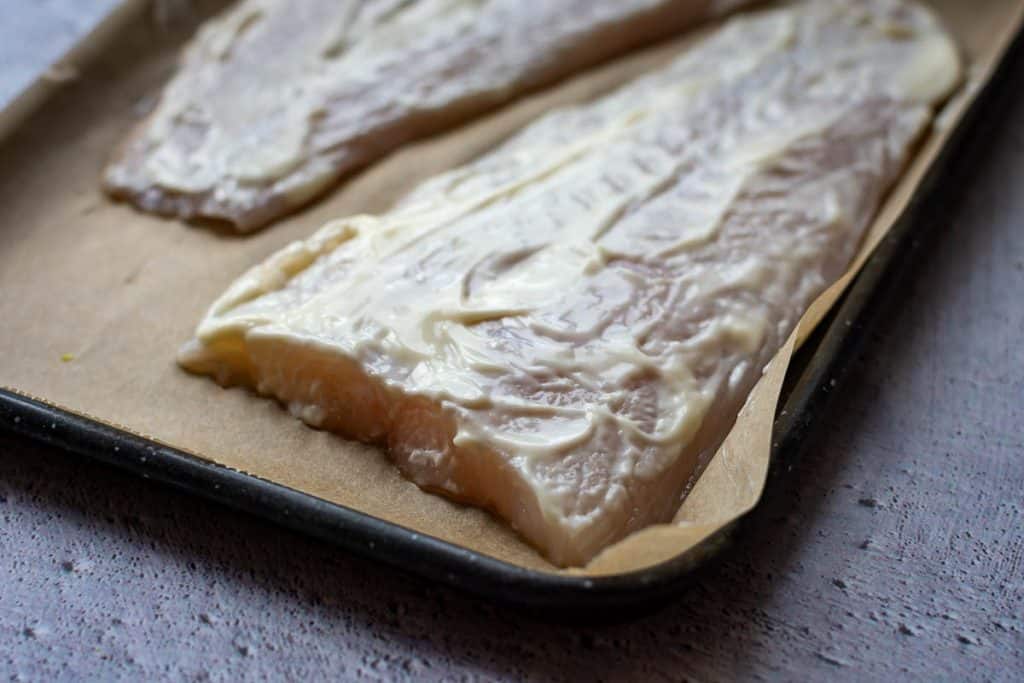 Mayonnaise spread on basa fish fillets.