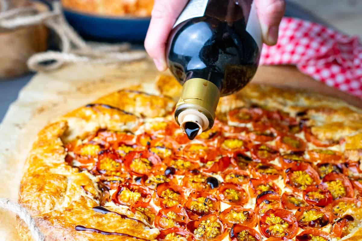 Drizzling cherry tomato galette with balsamic glaze.