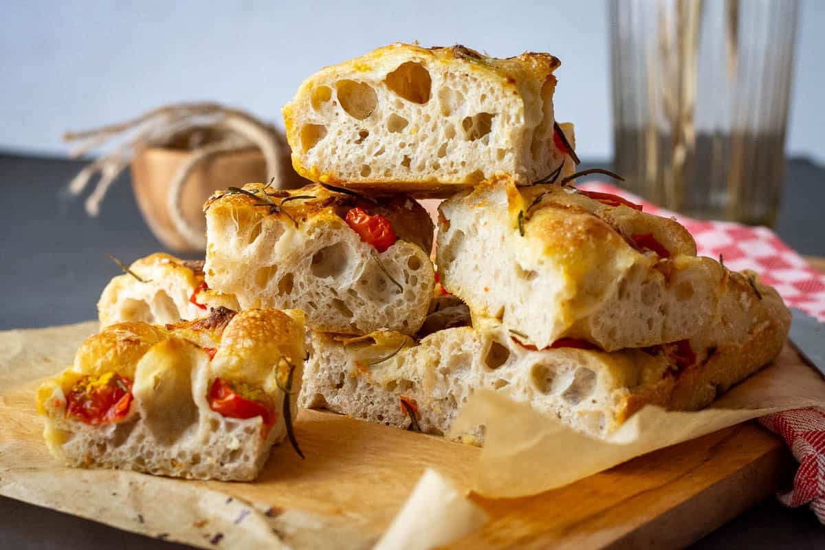 Cherry tomato sourdough focaccia cut into squares that are stacked on top of each other.