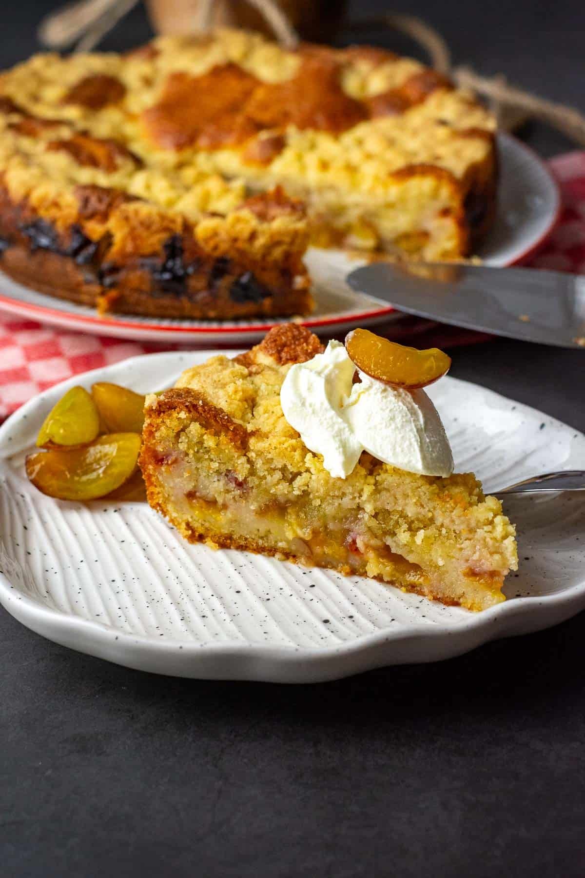 A slice of sourdough plum cake on a white plate with creme fraiche.