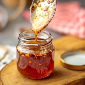 Homemade hot honey with smoked paprika being spooned into a small jar.
