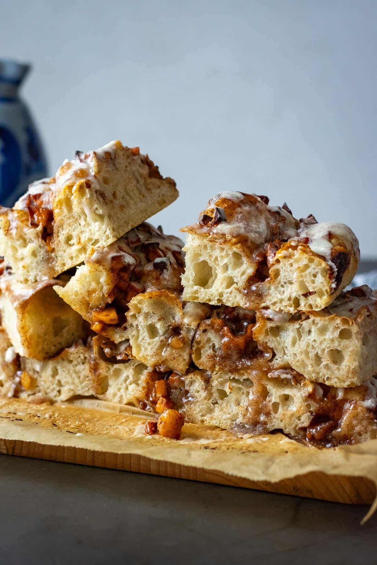 Cinnamon Apple Sourdough Focaccia cut into squares and stacked on a wooden board.