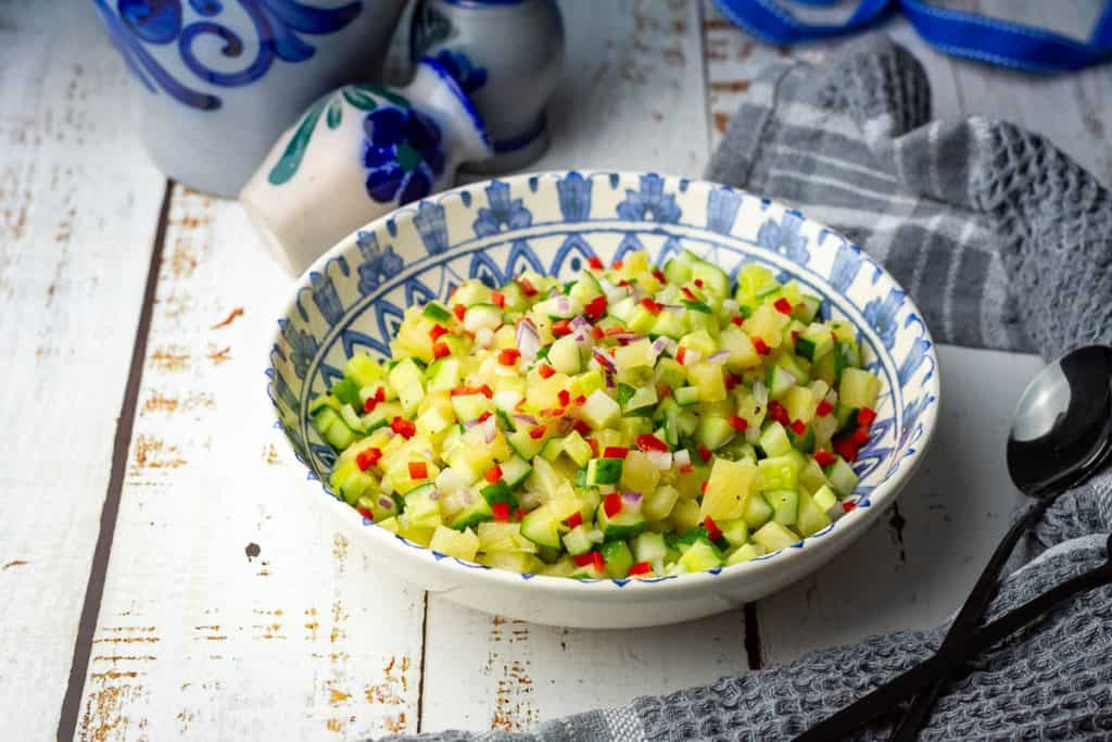Cucumber and pineapple salad served in a decorative white and blue bowl.