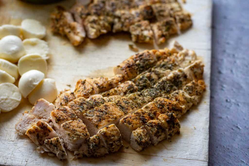 Cooked chicken cut into cubes on a wooden board.