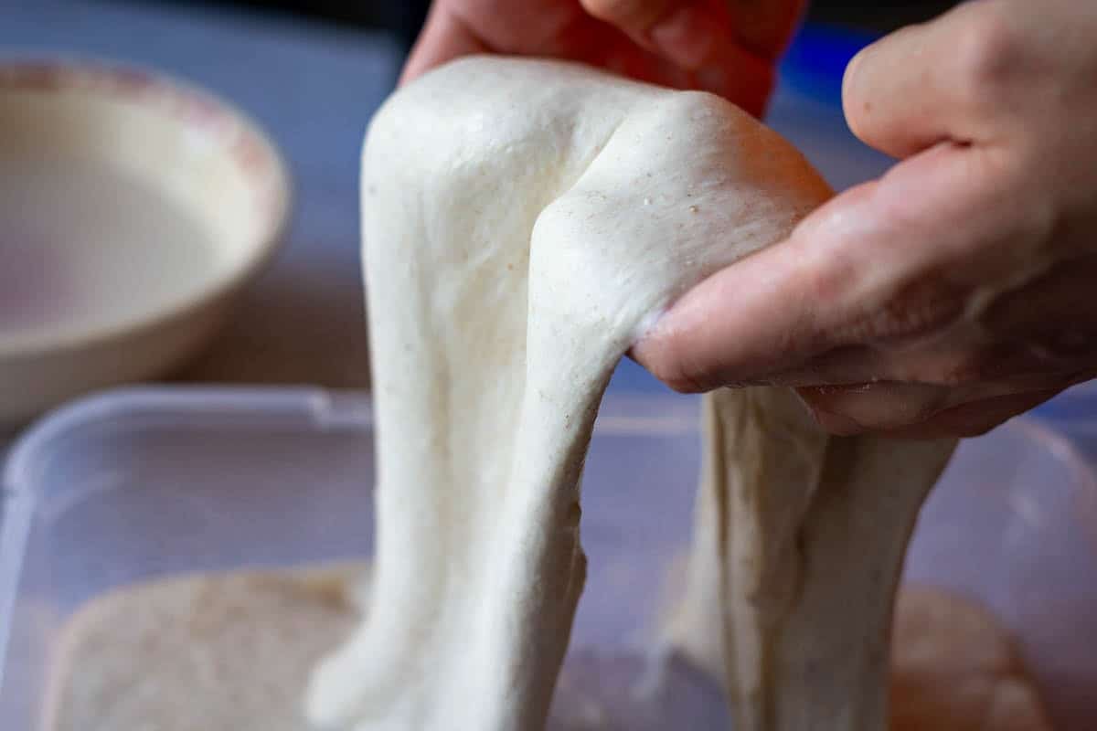Lifting the sourdough by the edges to coil fold.
