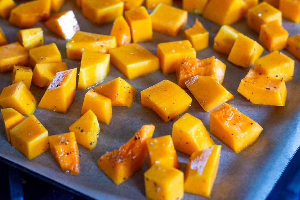 Cubed butternut squash arranged in a single layer on a baking sheet.
