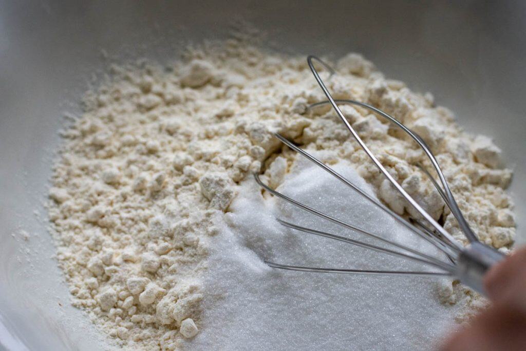 Mixing sugar and flour in a white bowl.