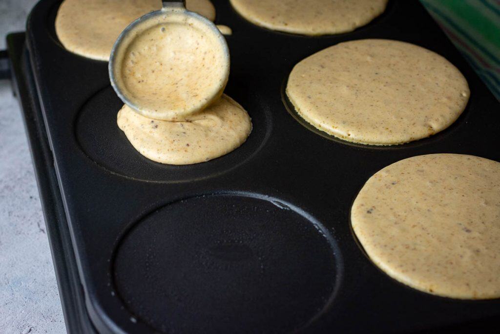 Pouring sourdough pancake batter onto a pancake griddle.