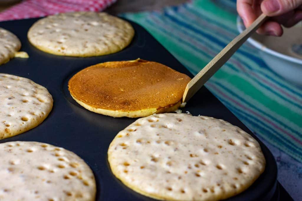 Flipping a sourdough pumpkin pancake with a wooden spatula.