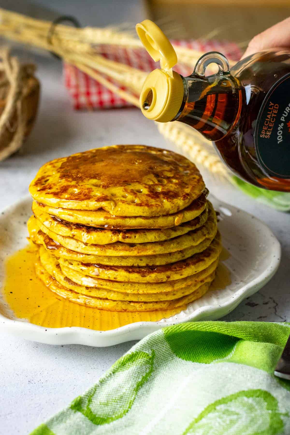 Maple syrup being poured on a stack of pumpkin sourdough pancakes.