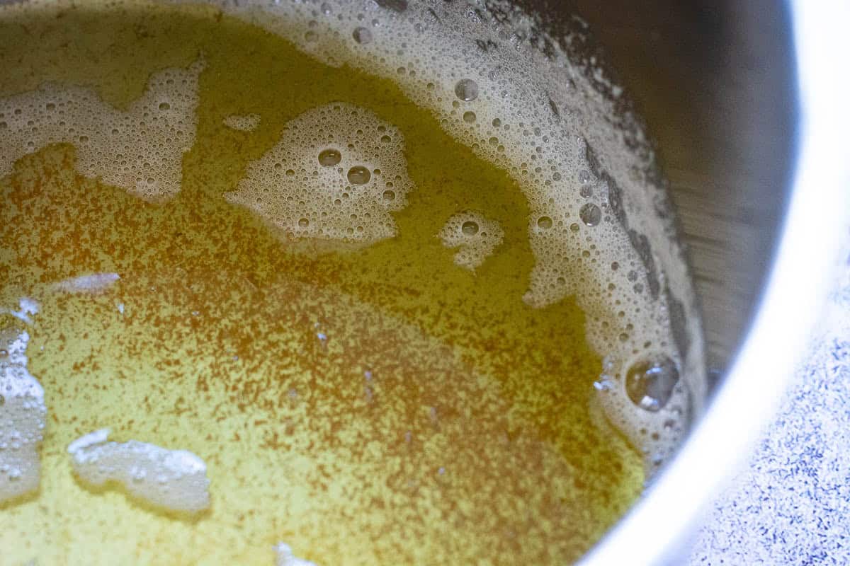 Brown specles start forming in butter being heating in a pan.