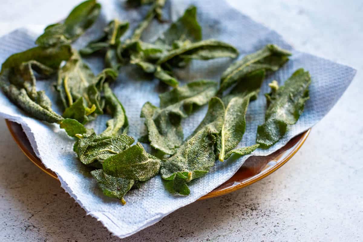 Crispy sgae leaves arranged on a paper towel lined plate.