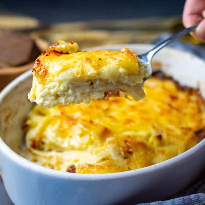 Dauphinoise Parsnip Gratin portion being lifted out of a casserole dish.
