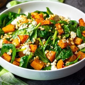 Spinach, butternut squash and feta salad in a large white bowl.